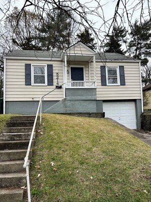A two-story house with a front porch, a garage, and a set of stone steps leading to the front door. - Charloe House: 2BR + Bonus Room, Near Cincinnati Attractions (Cincinnati)