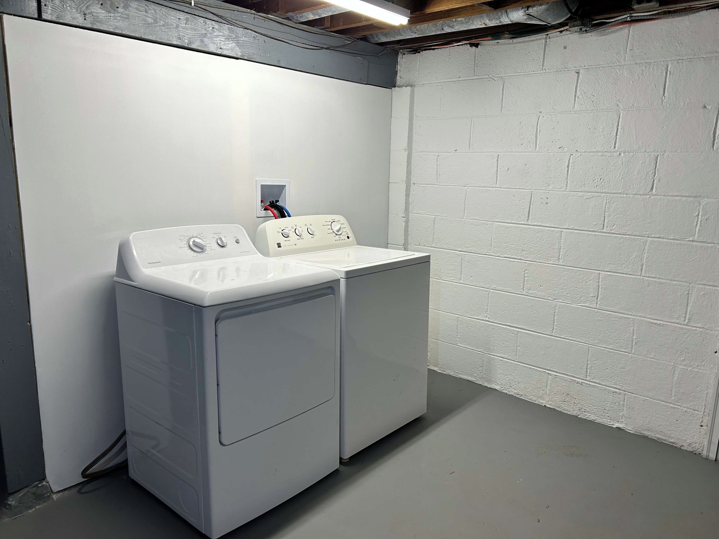 A laundry area with two white front-loading washing machines and a utility wall with electrical outlets.