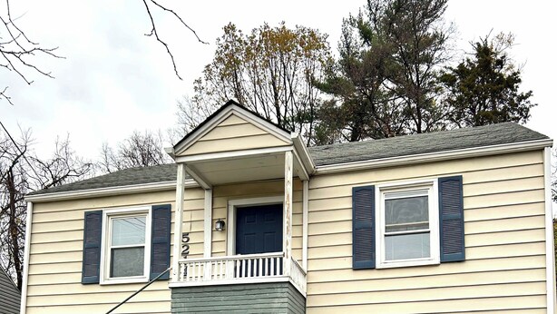 A two-story house with a front porch, a garage, and a small balcony.
