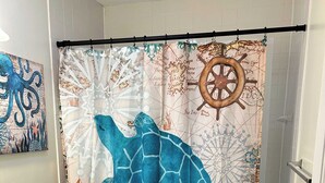 A bathroom with a sea turtle-themed shower curtain, a toilet, and a sink.