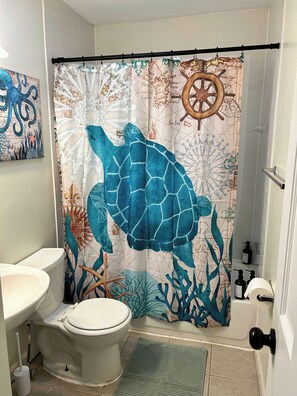 A bathroom with a sea turtle-themed shower curtain, a toilet, and a sink.