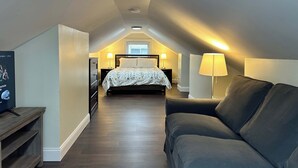 A bedroom with a bed, bedside lamps, a TV, and a sofa.