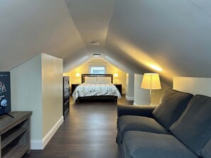A bedroom with a bed, bedside lamps, a TV, and a sofa.
