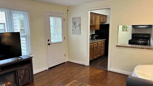 A living room with a TV, fireplace, and a dining area with wooden cabinets and a kitchen in the background.