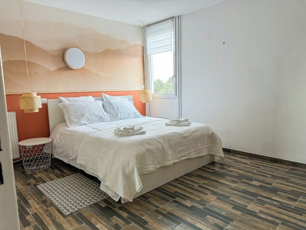 Un dormitorio con una cama, un espejo redondo, una ventana y un tapete estampado.
