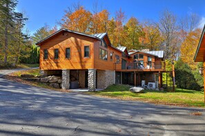 A log cabin with a stone foundation, a covered porch, and a stone fireplace.