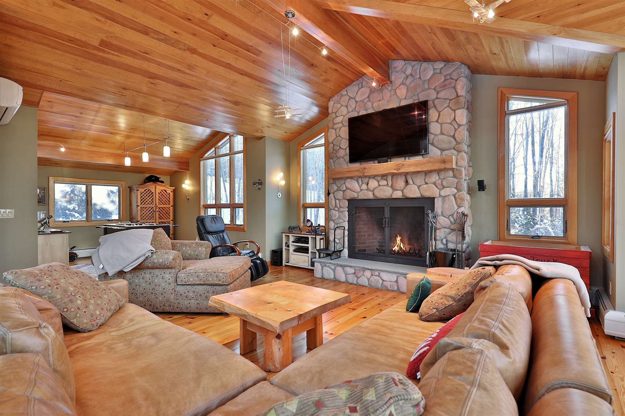 Ein gemütliches Wohnzimmer mit Kamin aus Stein, Ledersofas und Holzboden.