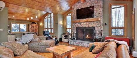 Ein gemütliches Wohnzimmer mit Kamin aus Stein, Ledersofas und Holzboden.