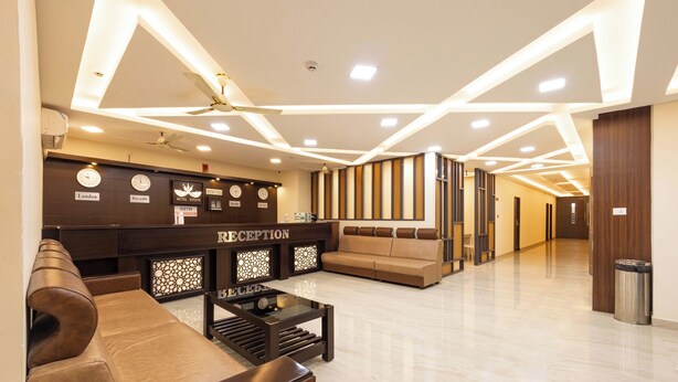 A hotel reception area with a reception desk, seating, and a modern ceiling design.