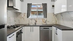Une cuisine moderne avec des meubles blancs, un lave-vaisselle en acier inoxydable et une cuisinière à gaz.