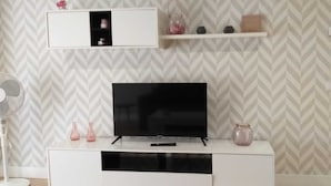 A modern living room with a flat-screen TV on a white entertainment unit, a fan, and decorative vases. - APARTMENTS NAJERA. Comfort for an exceptional rest. (Nájera)