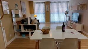 A modern living room with a dining area, featuring a white table, chairs, a TV, and a fireplace. - APARTMENTS NAJERA. Comfort for an exceptional rest. (Nájera)