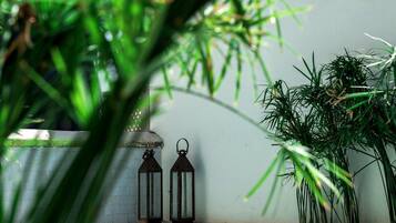 Una piscina con dos faroles y plantas al fondo.