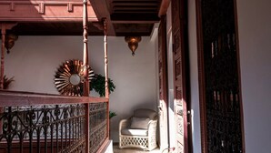 A corridor with a wooden railing, a patterned rug, and a chair.