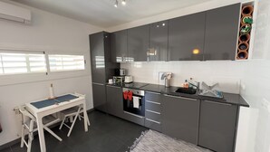 Una cucina moderna con mobili scuri, un piano di lavoro nero e un piccolo angolo ristoro con tavolo e sedie.