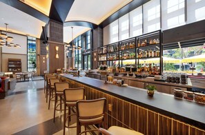 A modern bar area with a long counter, multiple seating options, and a well-stocked liquor shelf.