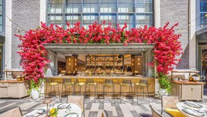 An outdoor bar area with a bar counter, seating, and a floral arch.