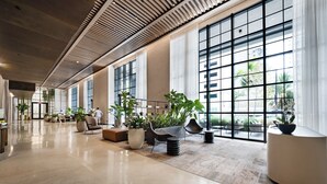 A spacious lobby with large windows, modern seating, and potted plants.