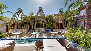 Un área junto a la piscina con sillones de descanso, una piscina pequeña y estructuras esféricas decorativas.