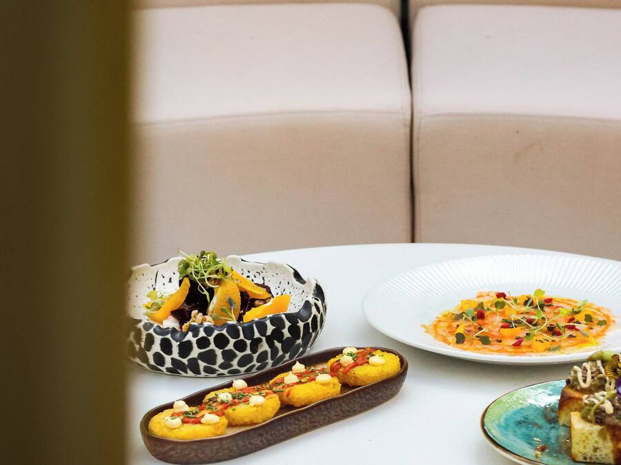 Una mesa con varios platos, incluyendo un bol con diseño decorativo, un plato con una ensalada colorida y una bandeja con alimentos.