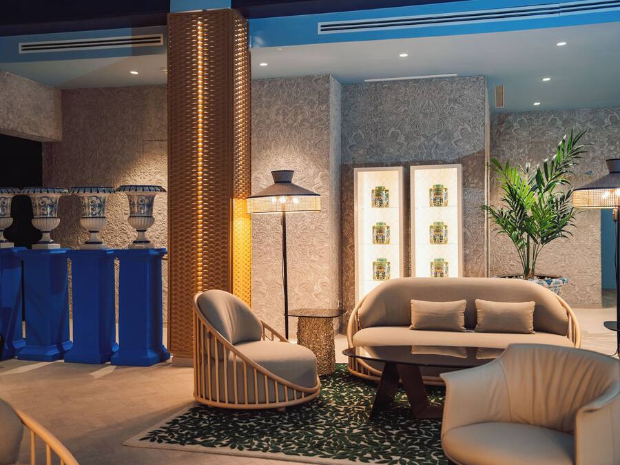 A modern lounge area with a sofa, chairs, a coffee table, a floor lamp, and a decorative plant.