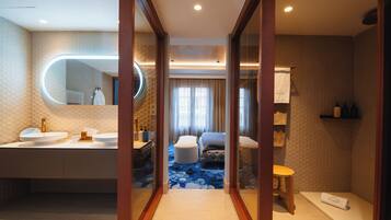 Un baño moderno con un espejo redondo, dos lavamanos, una bañera y una zona de ducha.