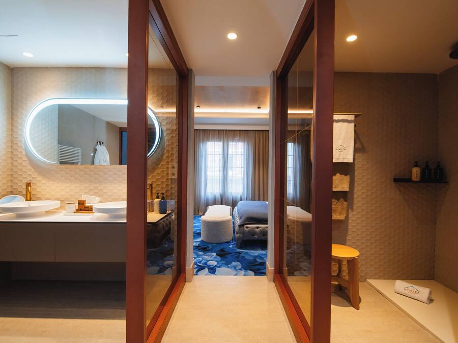 Un baño moderno con un espejo redondo, dos lavamanos, una bañera y una zona de ducha.
