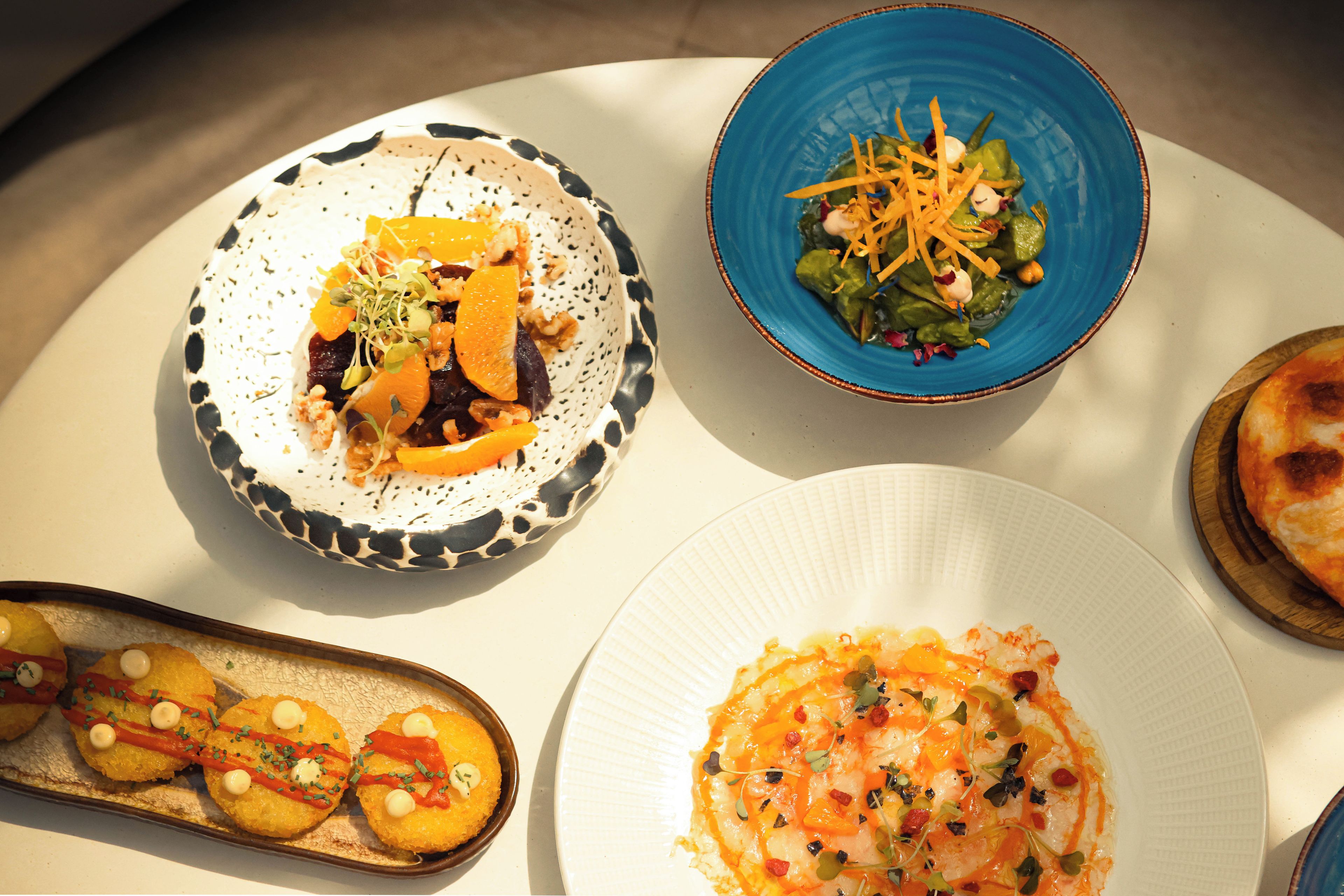 Variedad de platos en una mesa, como una ensalada, un postre y lo que parece ser un plato principal.