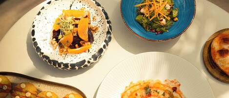 A variety of dishes on a table, including a salad, a dessert, and what appears to be a main course.