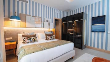 A hotel room with a large bed, a wardrobe, a desk, and a TV on the wall.
