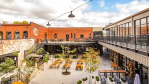 Un patio con mobiliario exterior, una escalera y una combinación de arquitectura de ladrillo y diseño moderno.