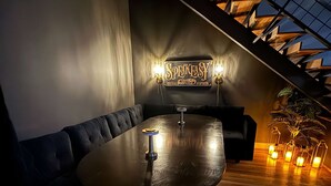 Un área de estar moderna con una mesa redonda, asientos de cuero negro y una escalera con diseño geométrico.