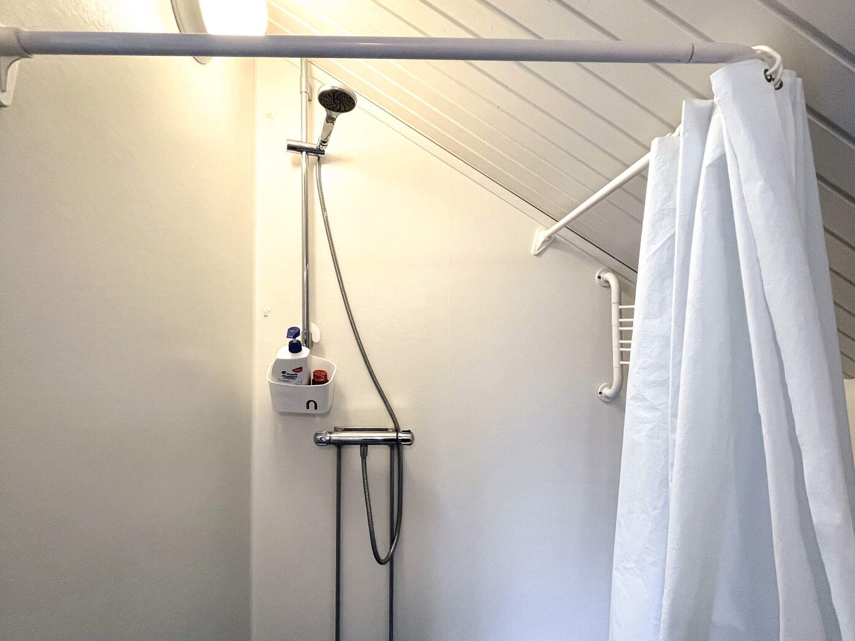 Un espace douche équipé d’un pommeau de douche à main, d’un robinet mural et d’un porte-serviettes.