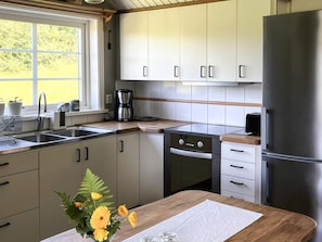 A modern kitchen with stainless steel appliances, a coffee maker, and a window with a view of greenery.