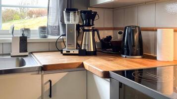 A kitchen with a coffee maker, a kettle, and a toaster on the counter.