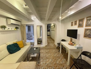 Cozy living space with a sofa, desk, and flat-screen TV.
