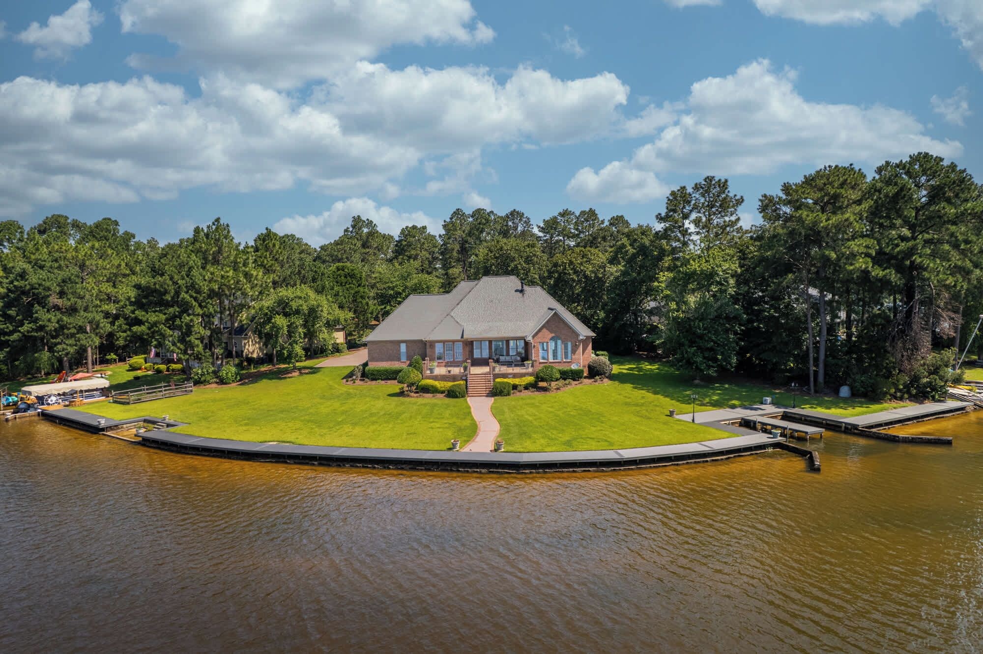 A house with a large lawn, a dock, and a pond.