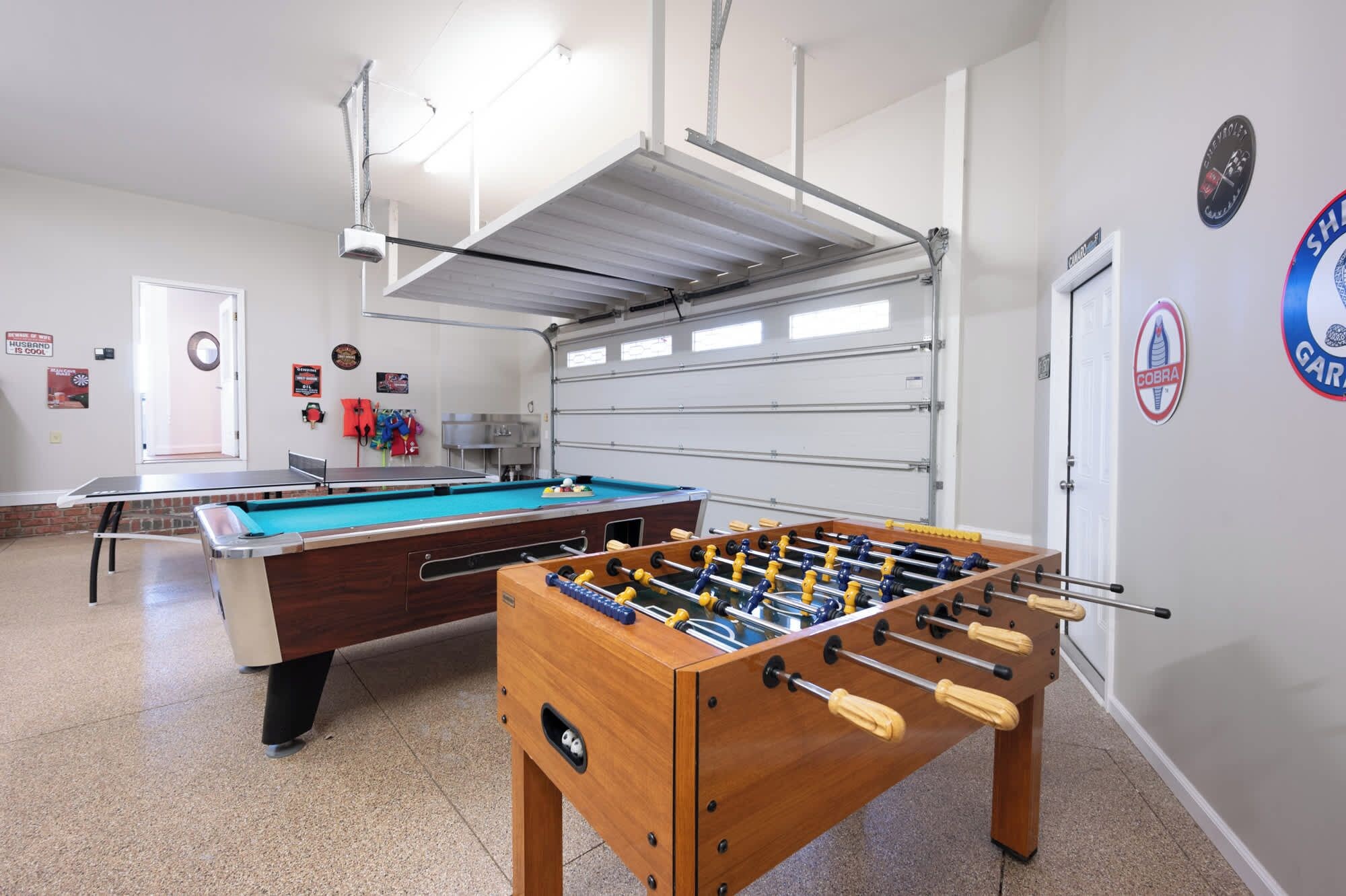 Une pièce équipée d’une table de billard, d’un baby-foot et d’une porte de garage.