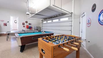 Une pièce équipée d’une table de billard, d’un baby-foot et d’une porte de garage.