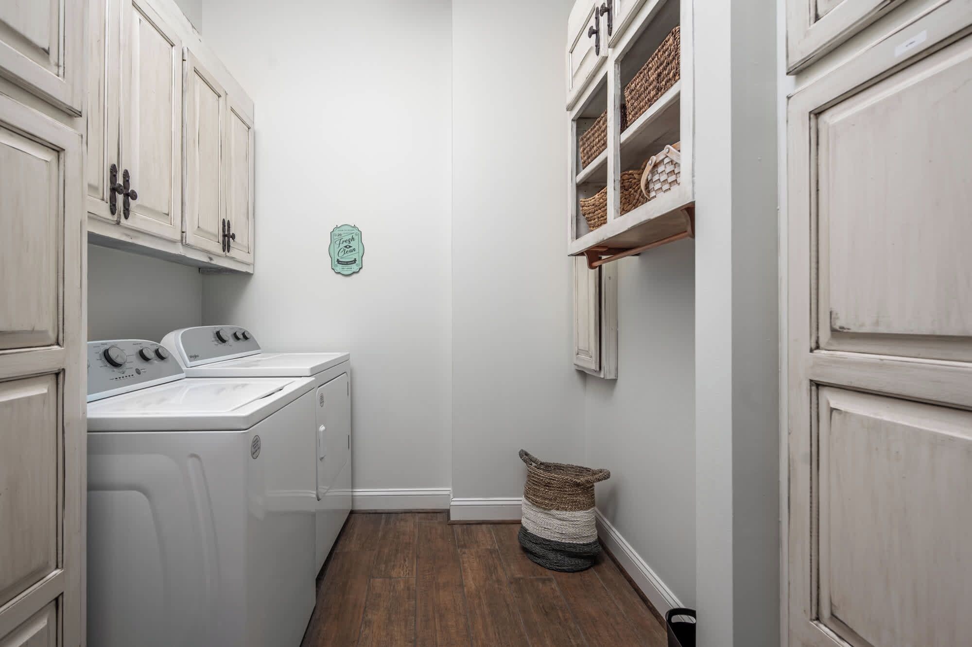 A laundry room with a washing machine, dryer, and shelves with baskets.