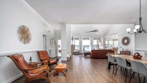A spacious living room with a wooden floor, leather armchairs, a sofa, and a dining area with a wooden table and chairs. - Lakefront Family Retreat with Game Room Fun (Sanford)