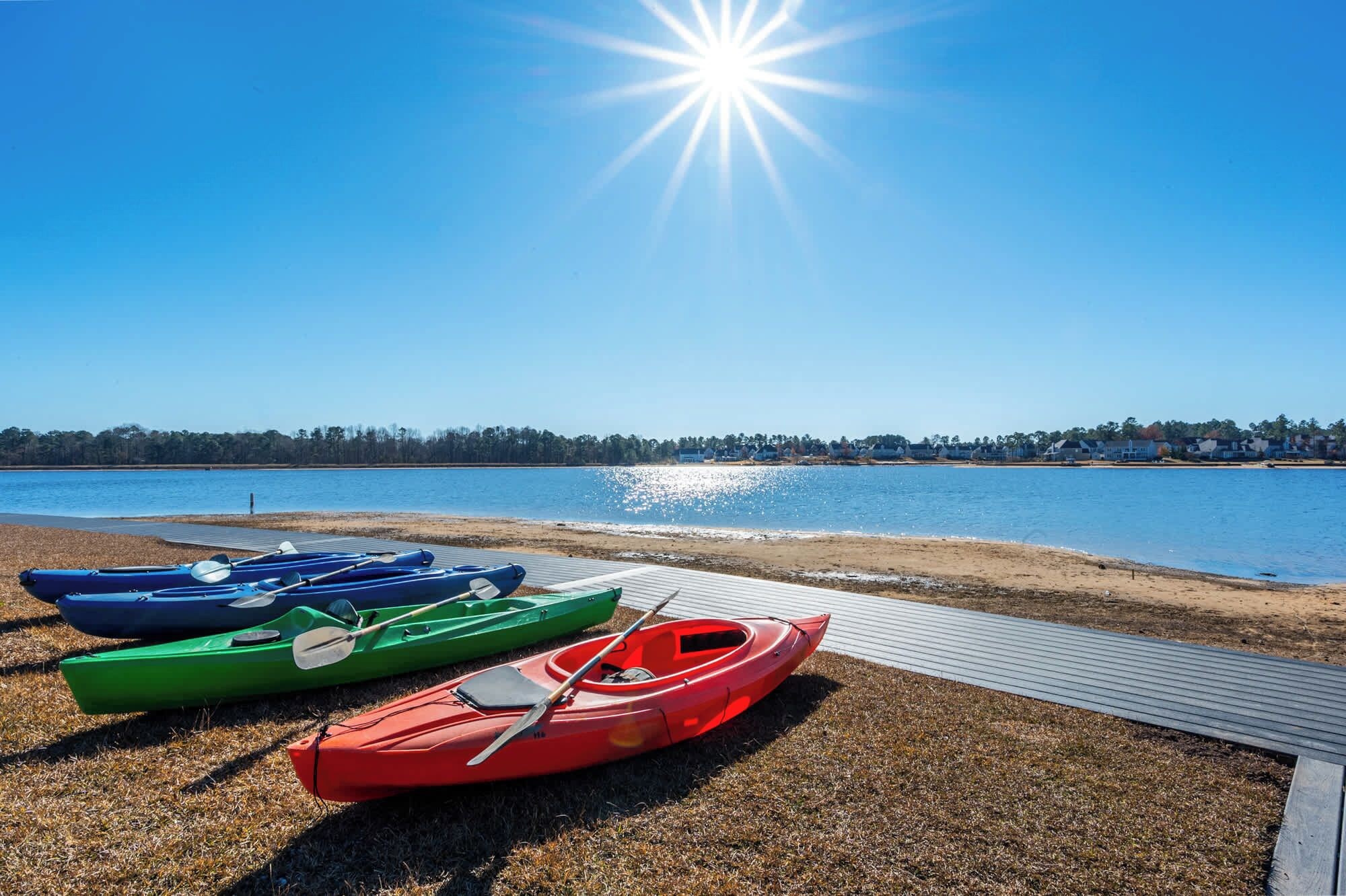 Vista de un lago con kayaks alineados en un muelle de madera.