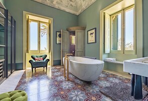 A bathroom with a freestanding bathtub, a vanity, and a chair.