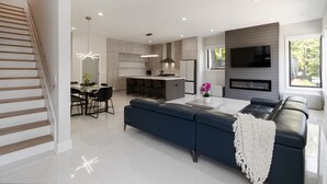 A modern kitchen with a dining area, a living room with a sofa, and a staircase. - Brand-New 3Story Home with Rooftop in Midtown (Atlanta)