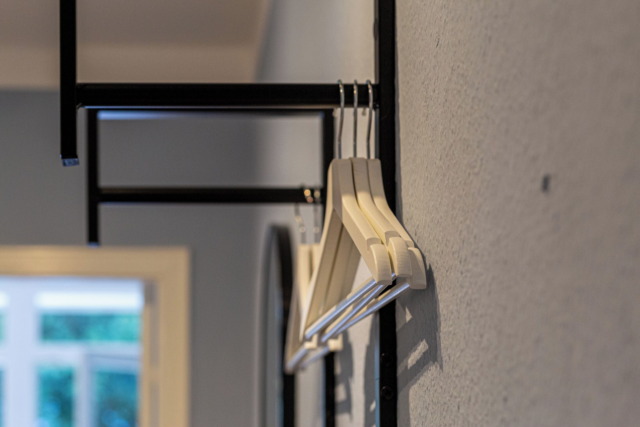 A wall-mounted rack with multiple white hangers.