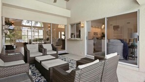 A spacious patio area with wicker furniture and a ceiling fan. - Waterfront 3BR retreat with heated pool, WiFi, and room for 8. (Marco Island)