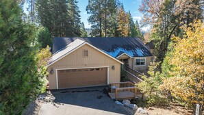 A single-story building with a garage, surrounded by trees and a clear sky. - Eagle Retreat ~ Mountain Escape • New • With AC (Shaver Lake)