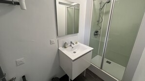 A bathroom with a white sink, mirror, and glass shower enclosure. - Amiens, l'appartement douillet 2-4P (Amiens)