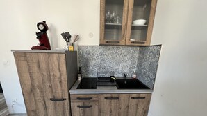 A compact kitchen with a built-in stove, wooden cabinets, and a backsplash with a geometric pattern. - Amiens, l'appartement douillet 2-4P (Amiens)