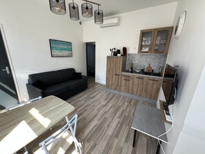 Een ruimtelijke zithoek met een bank, eettafel en kitchenette.